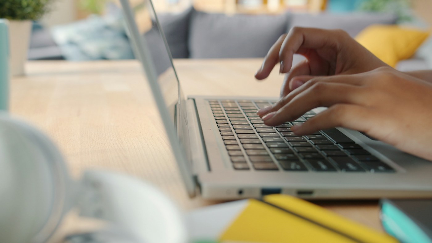 Hands working at a laptop on a desk